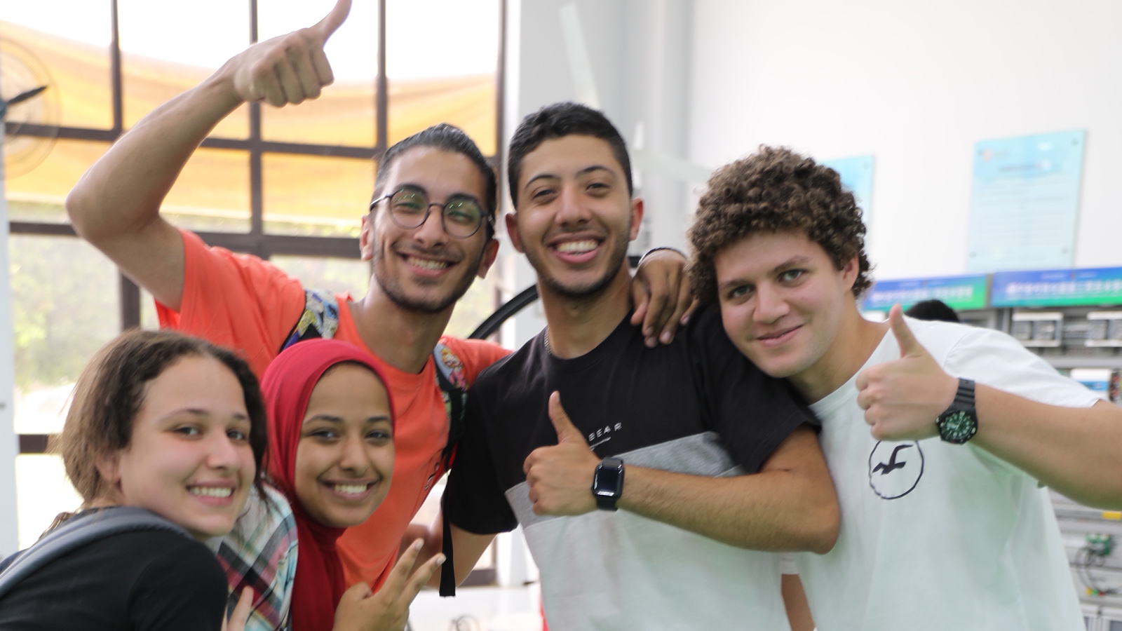 university students smiling with thumbs up