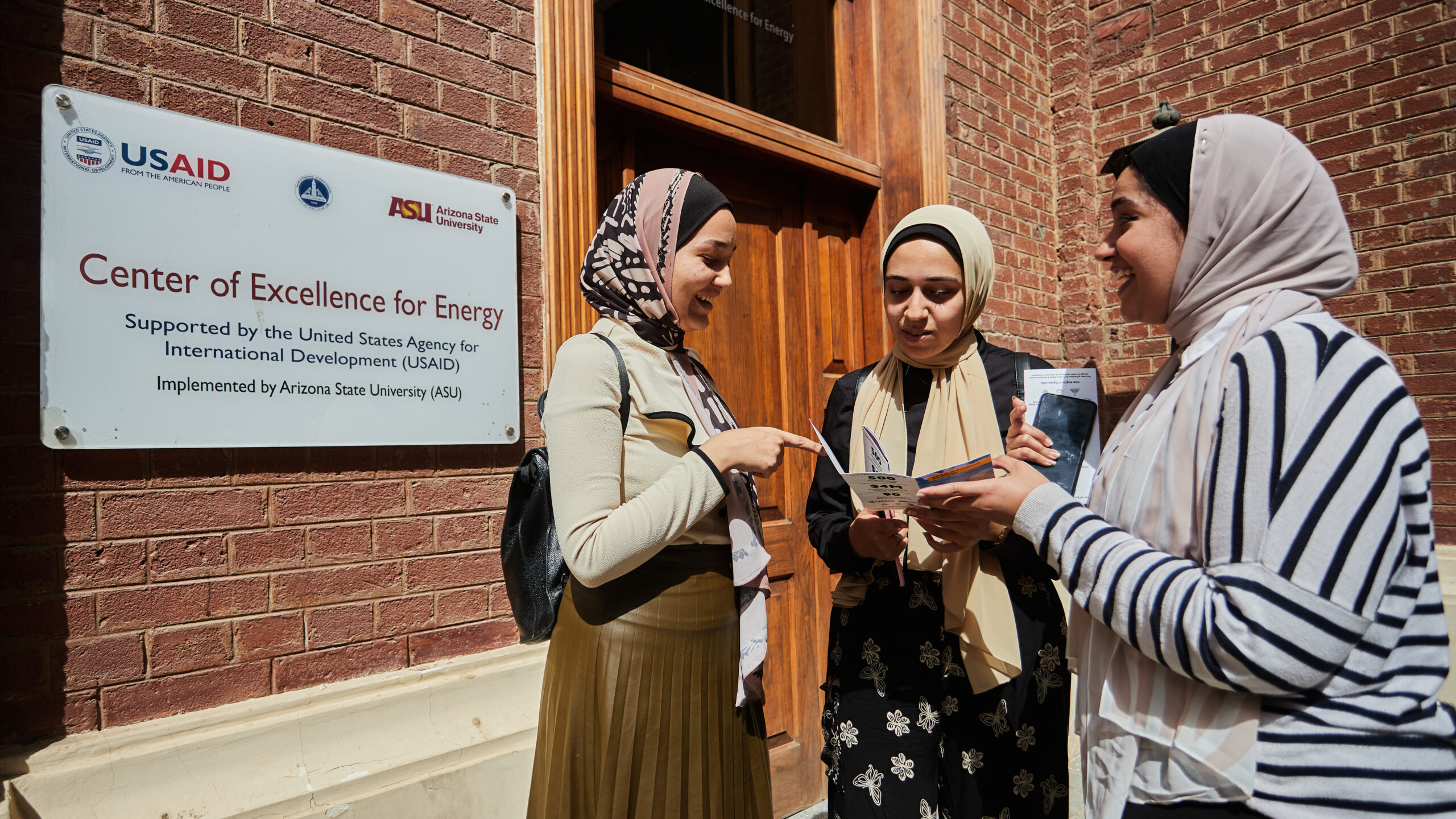Three female students standing near entrance to Center of Excellence for Energy