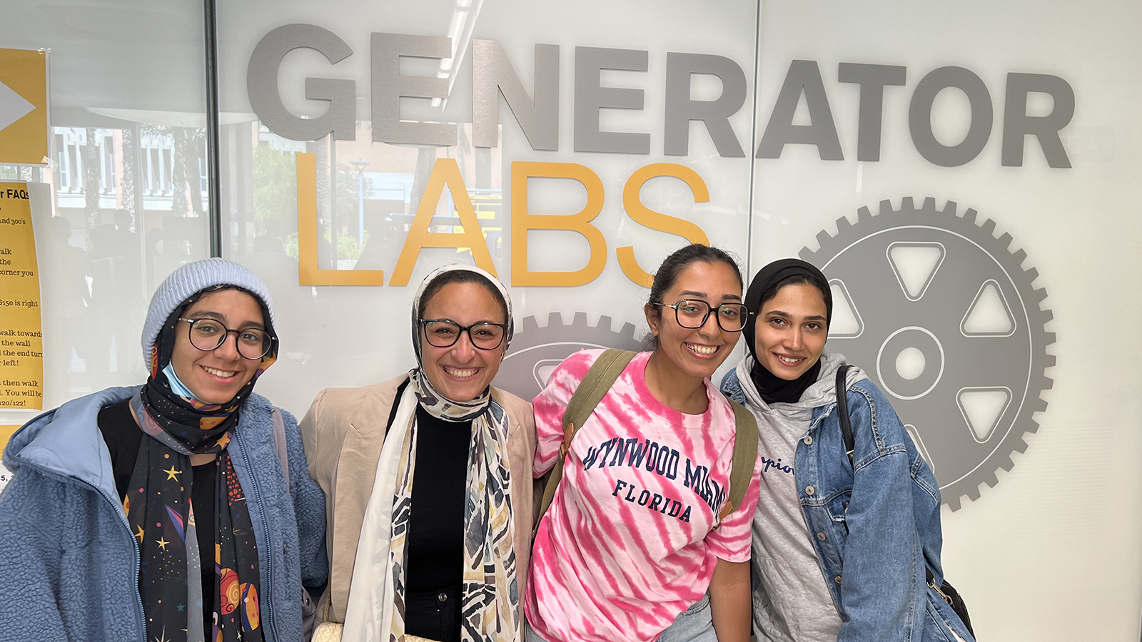 Four young women stand in front research laboratory