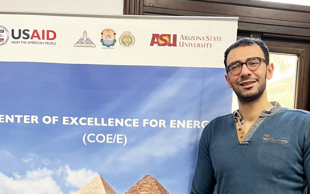 Male student standing in front of Center of Excellence for Energy sign